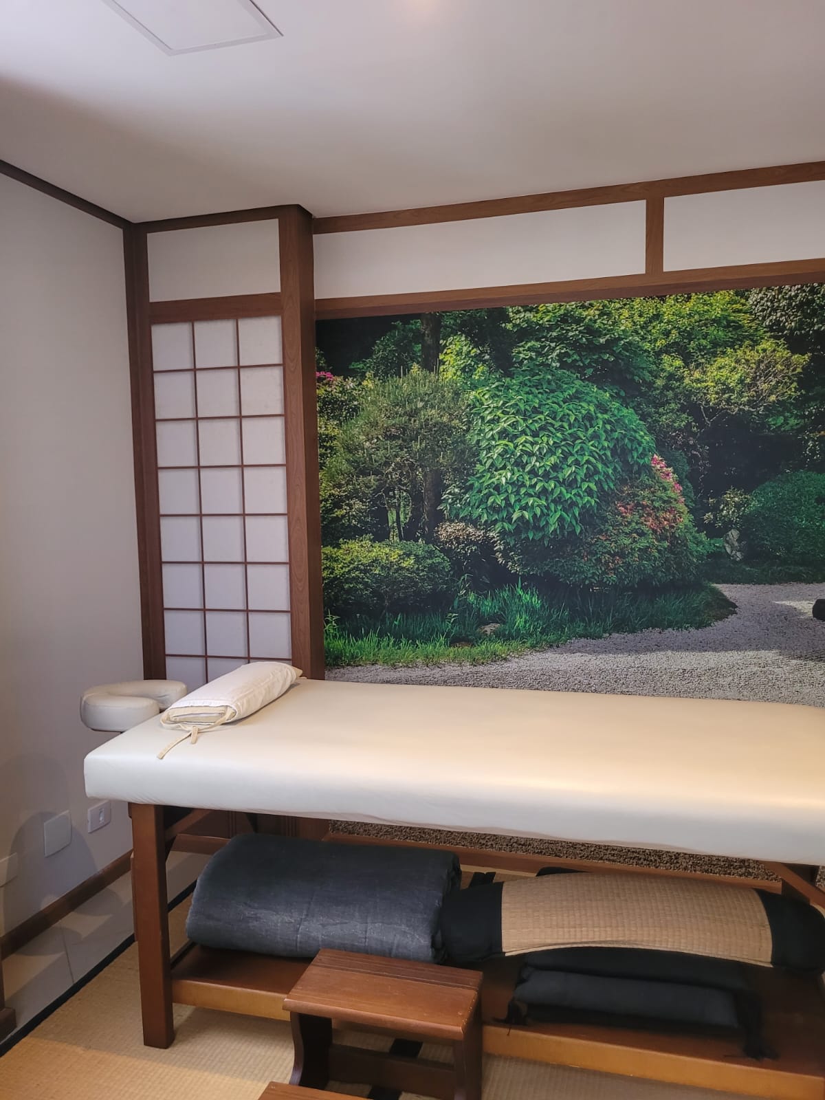 Sala de massagem do Augusto Maiolo Spa Shiatsu com maca e mural de jardim japonês